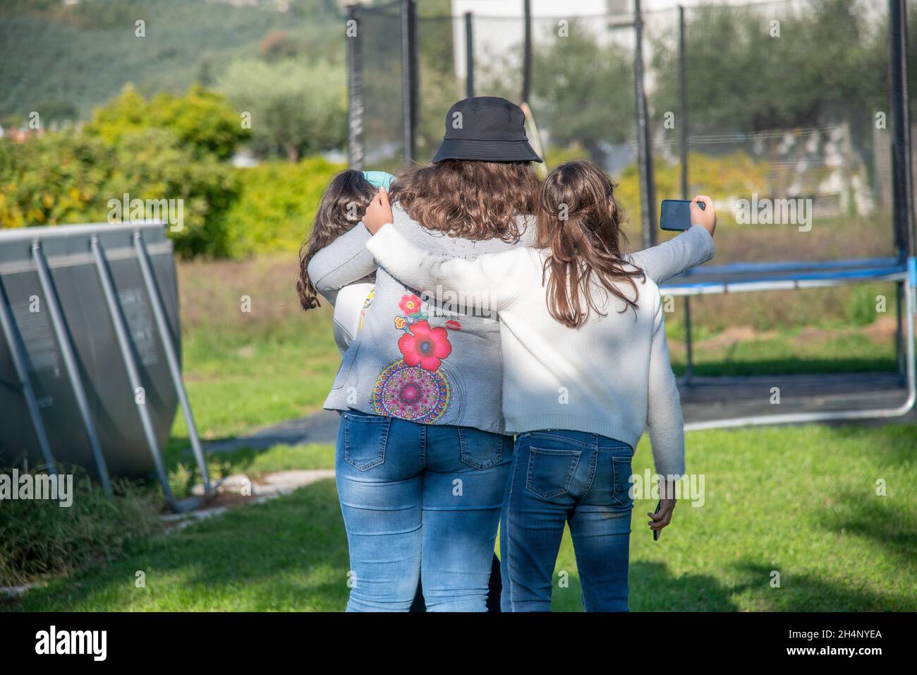 Trois jeunes filles jouant à l'extérieur en prenant des selfies dans le jardin Banque D'Images