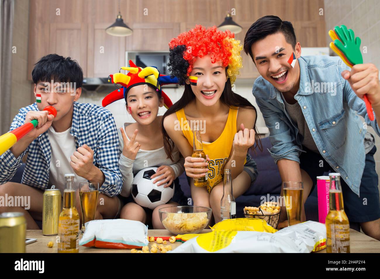 Les jeunes regardent des jeux sportifs dans le salon Banque D'Images