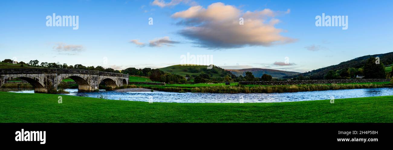 Vue panoramique en soirée sur le fleuve du pont historique en pierre qui enjambe les eaux coulées de la rivière Wharfe - Burnsall, Yorkshire Dales, Angleterre, Royaume-Uni. Banque D'Images