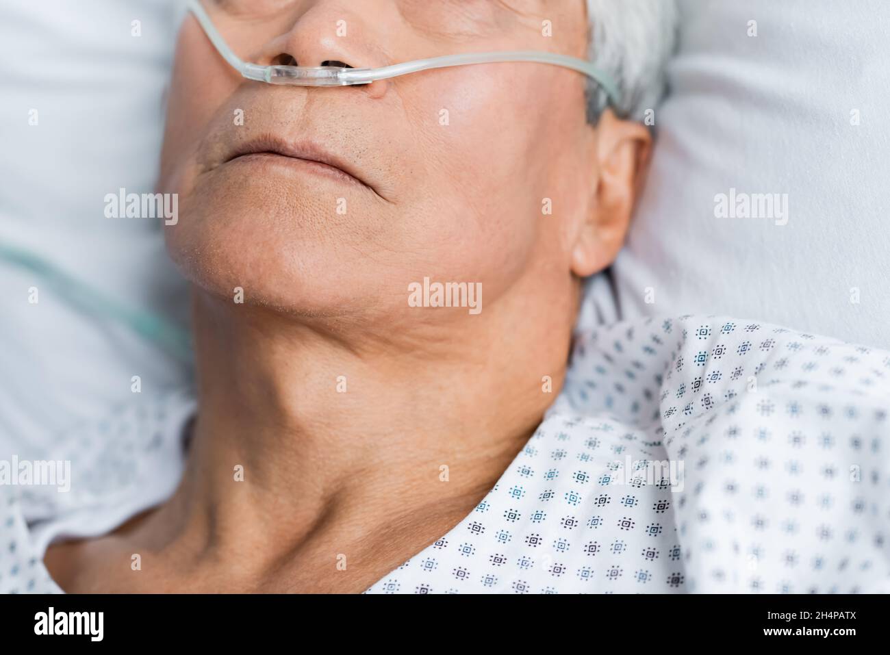 Vue rognée d'un patient lisse avec une canule nasale couchée sur le lit à l'hôpital Banque D'Images