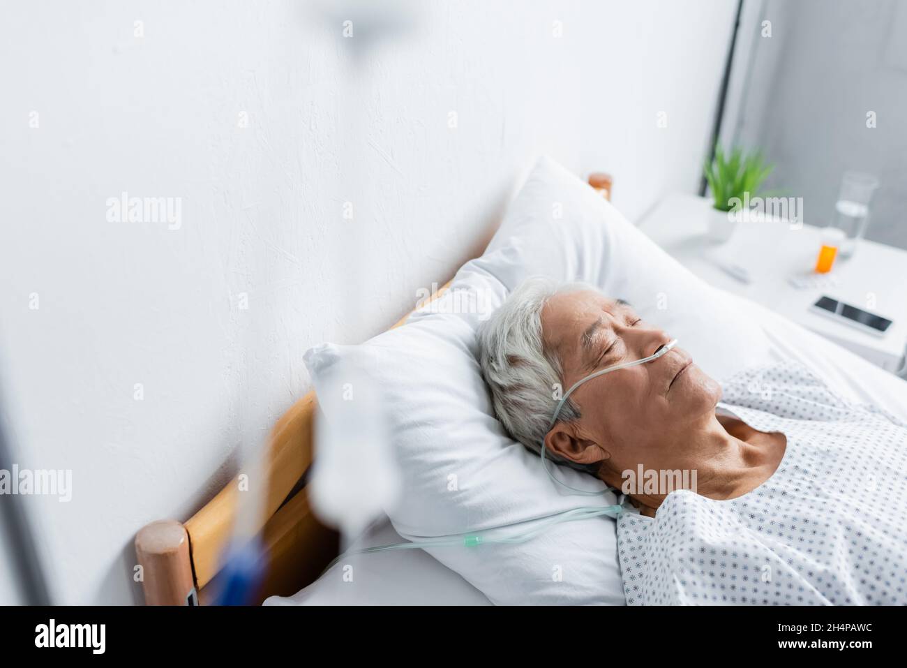 Patient asiatique avec canule nasale couchée sur le lit dans le service hospitalier Banque D'Images
