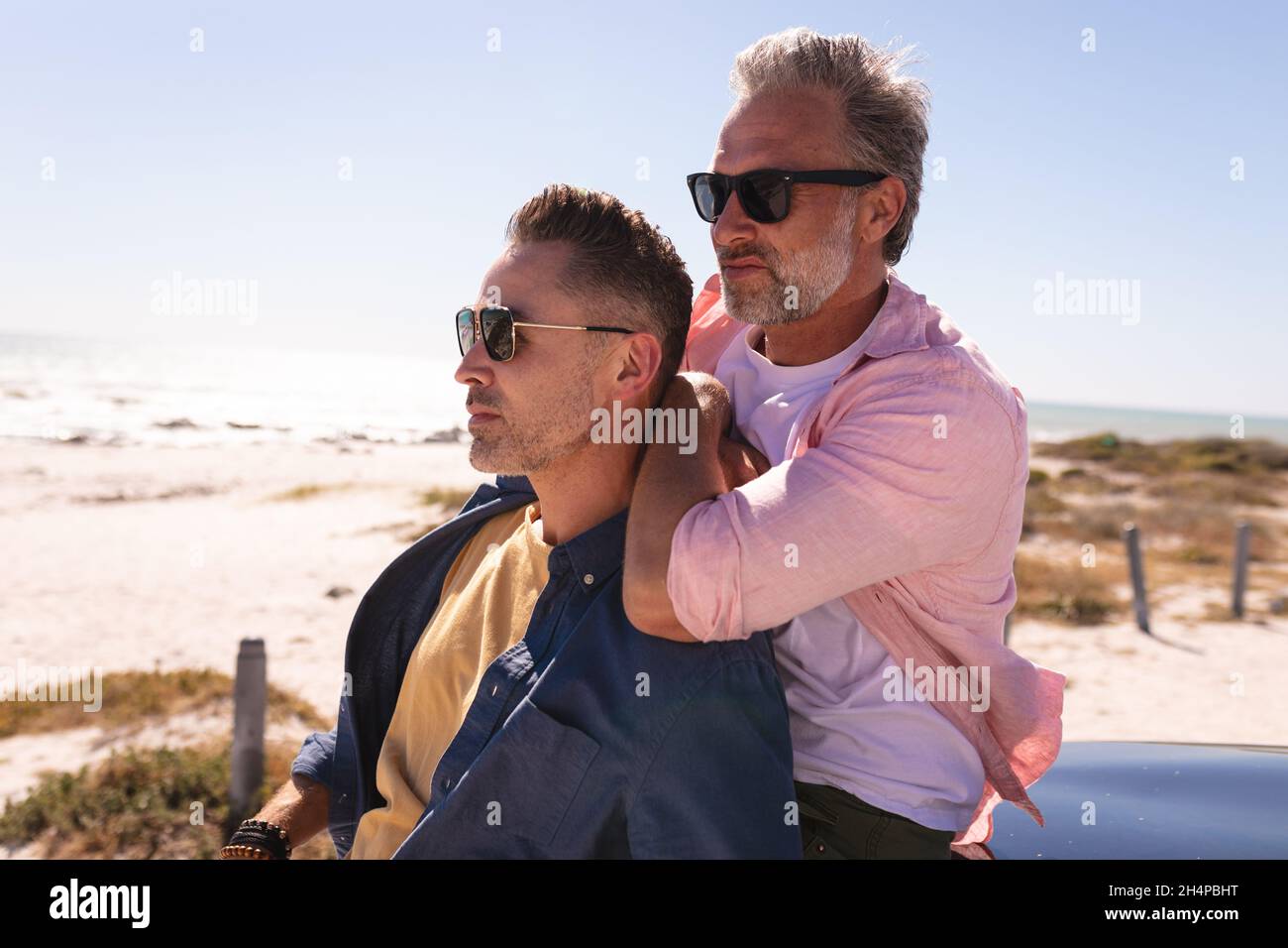Un couple de hommes gais et caucasiens heureux embrassant et profitant de la vue sur le bord de mer Banque D'Images