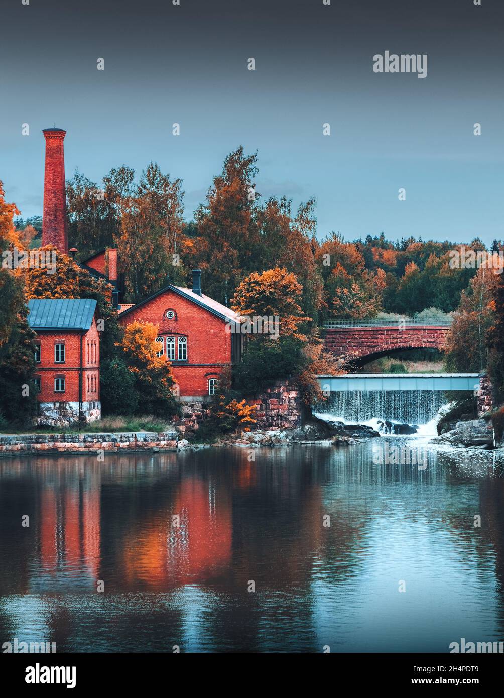 Paysage d'automne.Vieux bâtiments en briques reflétés dans l'eau.Murs rouges.Pont en pierre au-dessus de la petite cascade.Saison d'automne Moody.Architecture historique. Banque D'Images