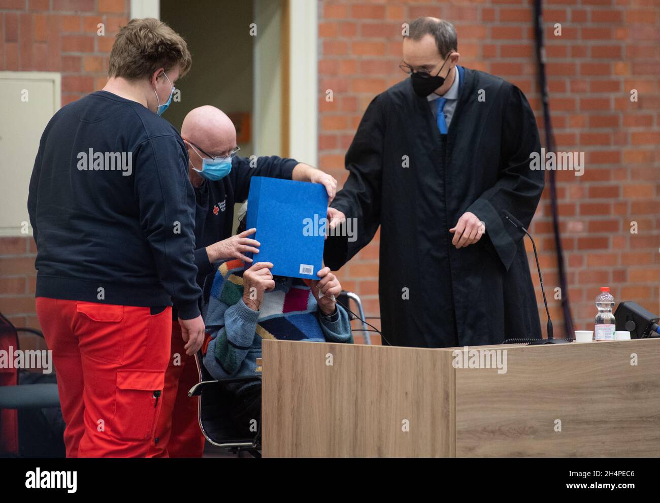 04 novembre 2021, Brandebourg, Brandebourg/Havel: Le défendeur (M) alléguait l'entrée d'un ancien garde de camp de concentration dans la salle d'audience.Sur la droite se trouve son avocat, Stefan Waterkamp.Le défendeur de 100 ans aurait aidé et encouragé le meurtre de milliers de détenus du camp de concentration de Sachsenhausen entre 1942 et 1945.Photo: Christophe GATEAU/dpa Banque D'Images