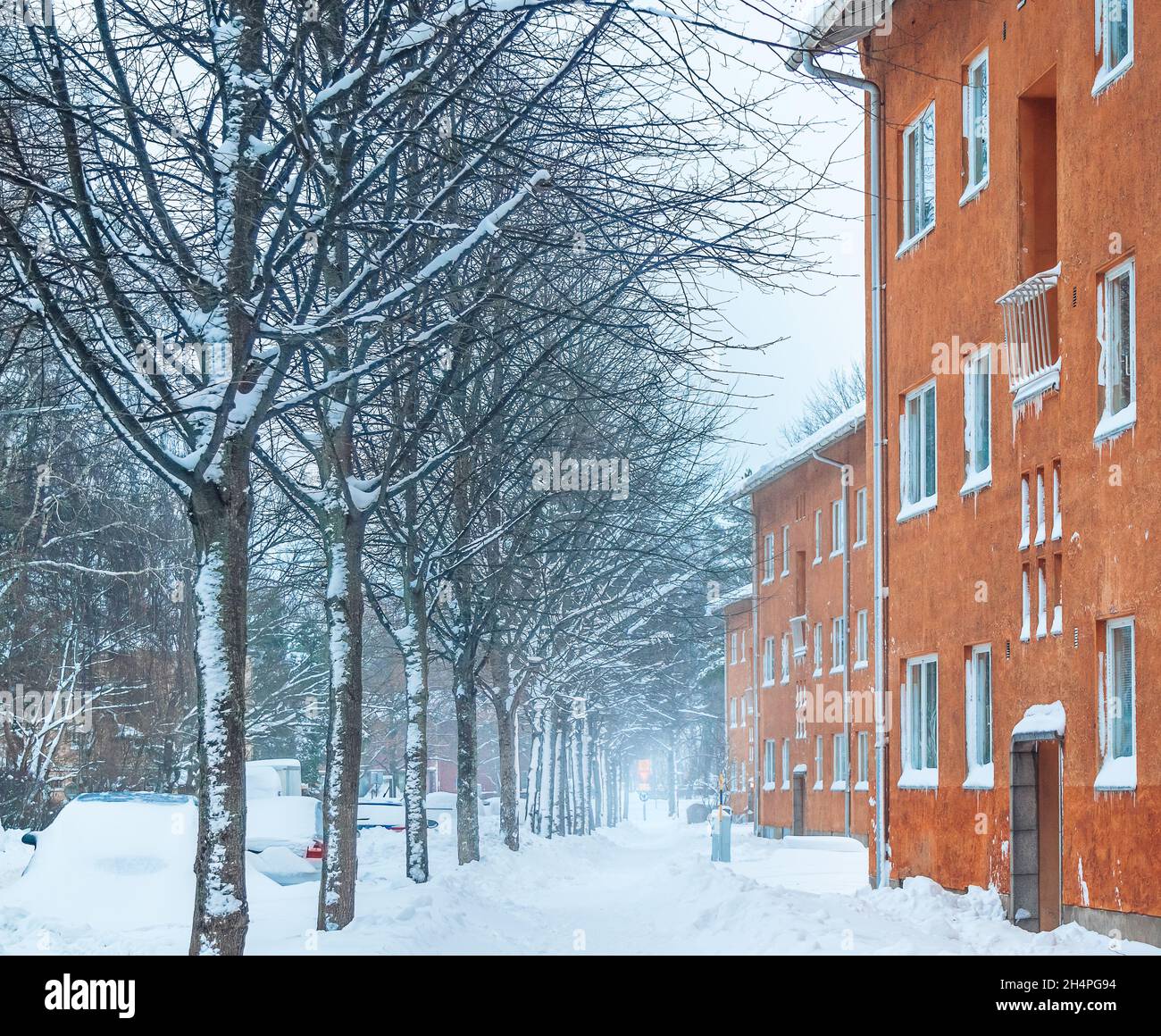 Façades de bâtiments orange dans une rue couverte de neige en hiver.Snowdrift sur une route dans le quartier résidentiel.Chute de neige à HELSINKI FINLANDE Blizzard Banque D'Images