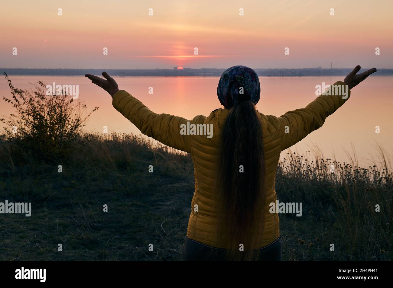 Coucher de soleil et la figure d'une femme avec les bras étirés et tenir l'horizon.Odessa Ukraine, estuaire de Belgogr Dnestrovsky. Banque D'Images