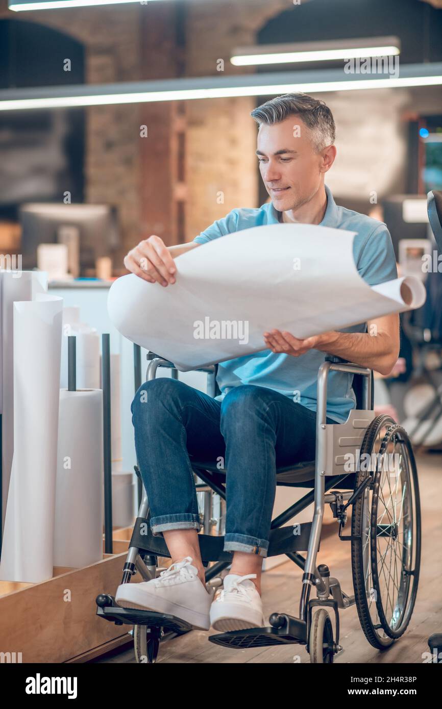 Homme en fauteuil roulant regardant le croquis avec plaisir Banque D'Images