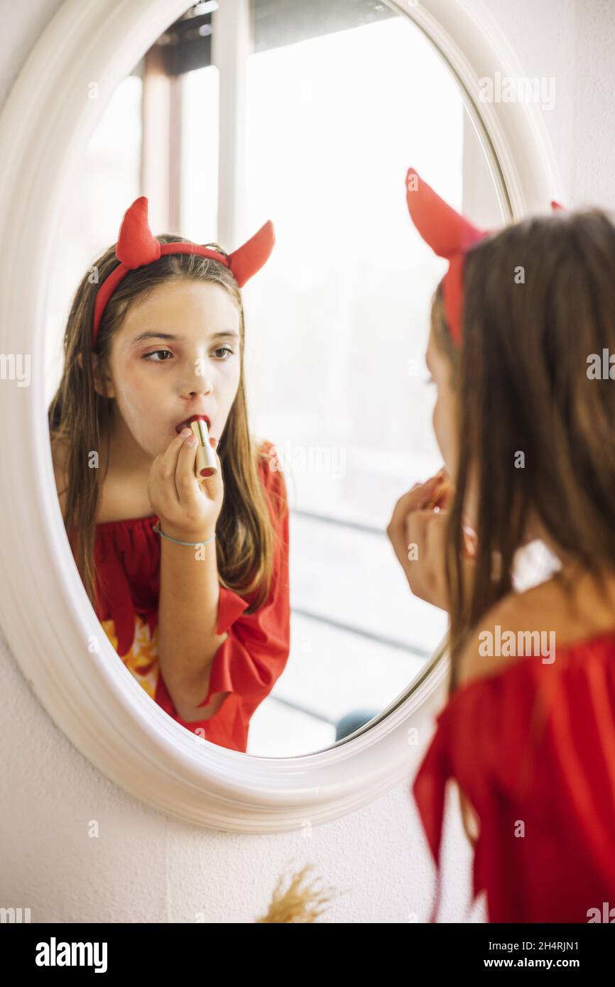 Jolie jeune fille mettant sur le maquillage du diable pour Halloween Banque D'Images