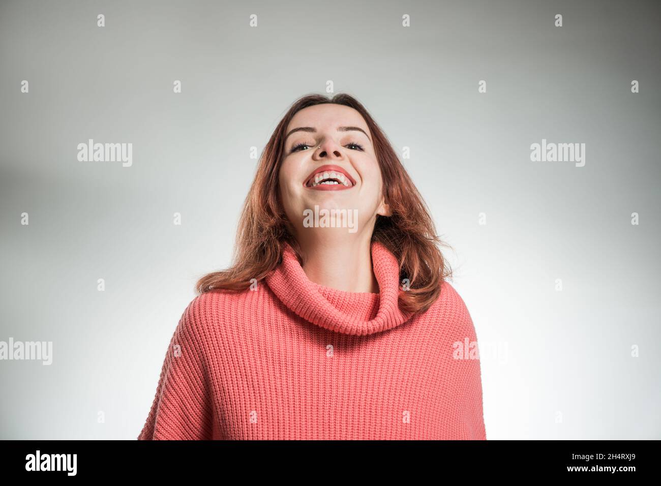 jeune femme riant portrait en chandail rose sur fond de studio Banque D'Images