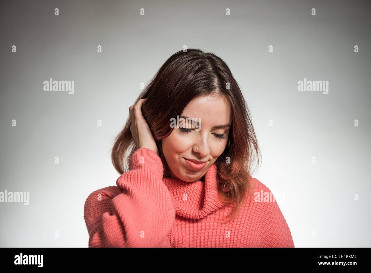 jeune femme timide portrait en chandail rose sur fond de studio Banque D'Images