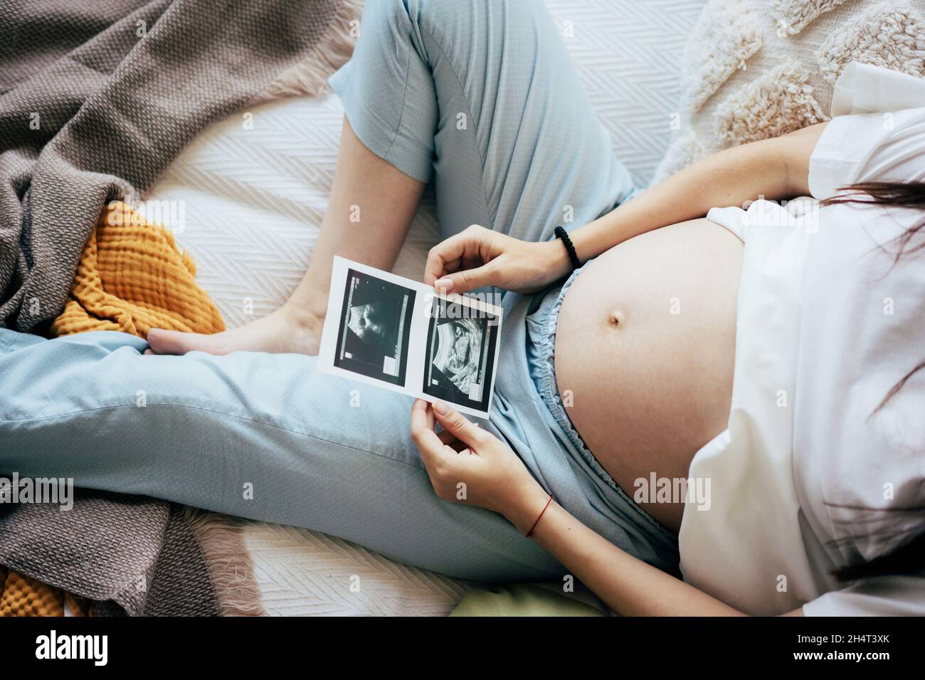 Femme enceinte méconnaissable au troisième trimestre allongé sur le lit regardant l'échographie médicale.Le concept d'une grossesse heureuse et en bonne santé expecta Banque D'Images
