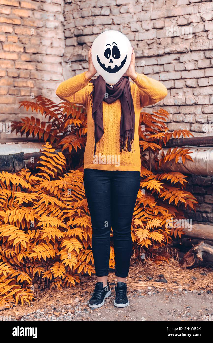 Fille dans la cour tenant ballon gonflable avec un mal visage dans ses  mains à l'extérieur heureux halloween concept carte de vacances style de  rue automne saison Costume Photo Stock - Alamy
