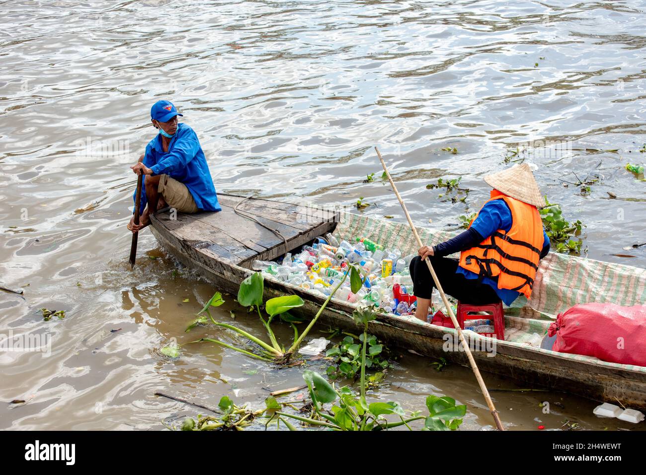 Les travailleurs pauvres ramassant des bouteilles en plastique qui polluent l'environnement sur le fleuve au Vietnam Banque D'Images