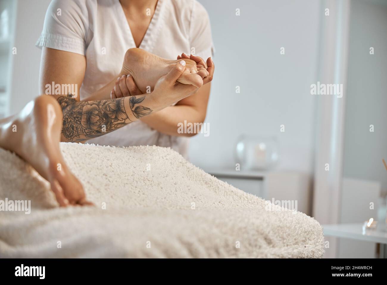 Professionnel confiant maître de massage fait des procédures à la femme caucasienne dans le cabinet moderne minimaliste Banque D'Images