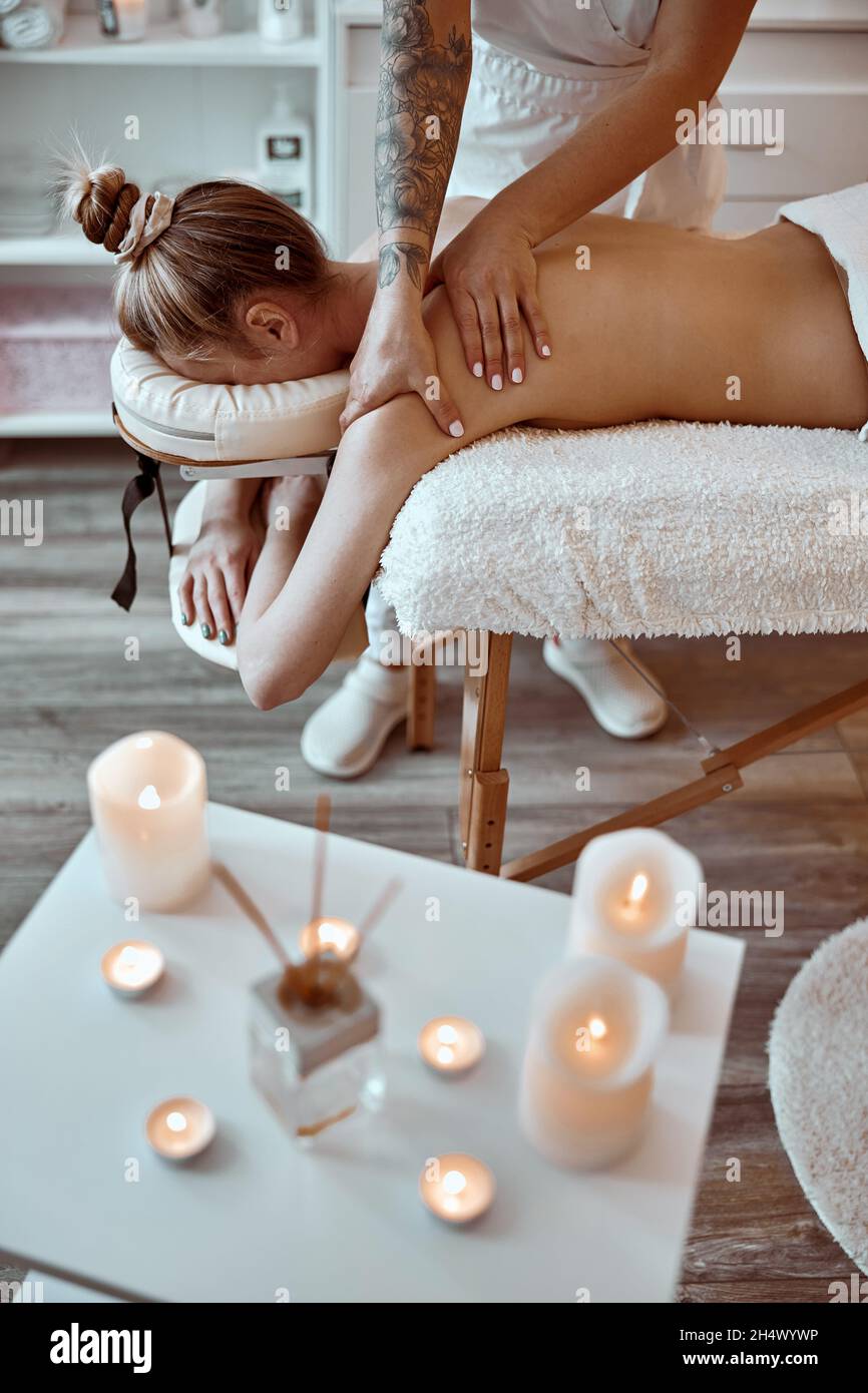 Professionnel confiant maître de massage fait des procédures à la femme caucasienne dans le cabinet moderne minimaliste Banque D'Images