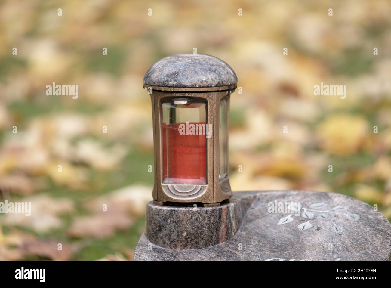 lanterne grave sur une petite pierre tombale avec des feuilles d'automne dans un arrière-plan flou Banque D'Images