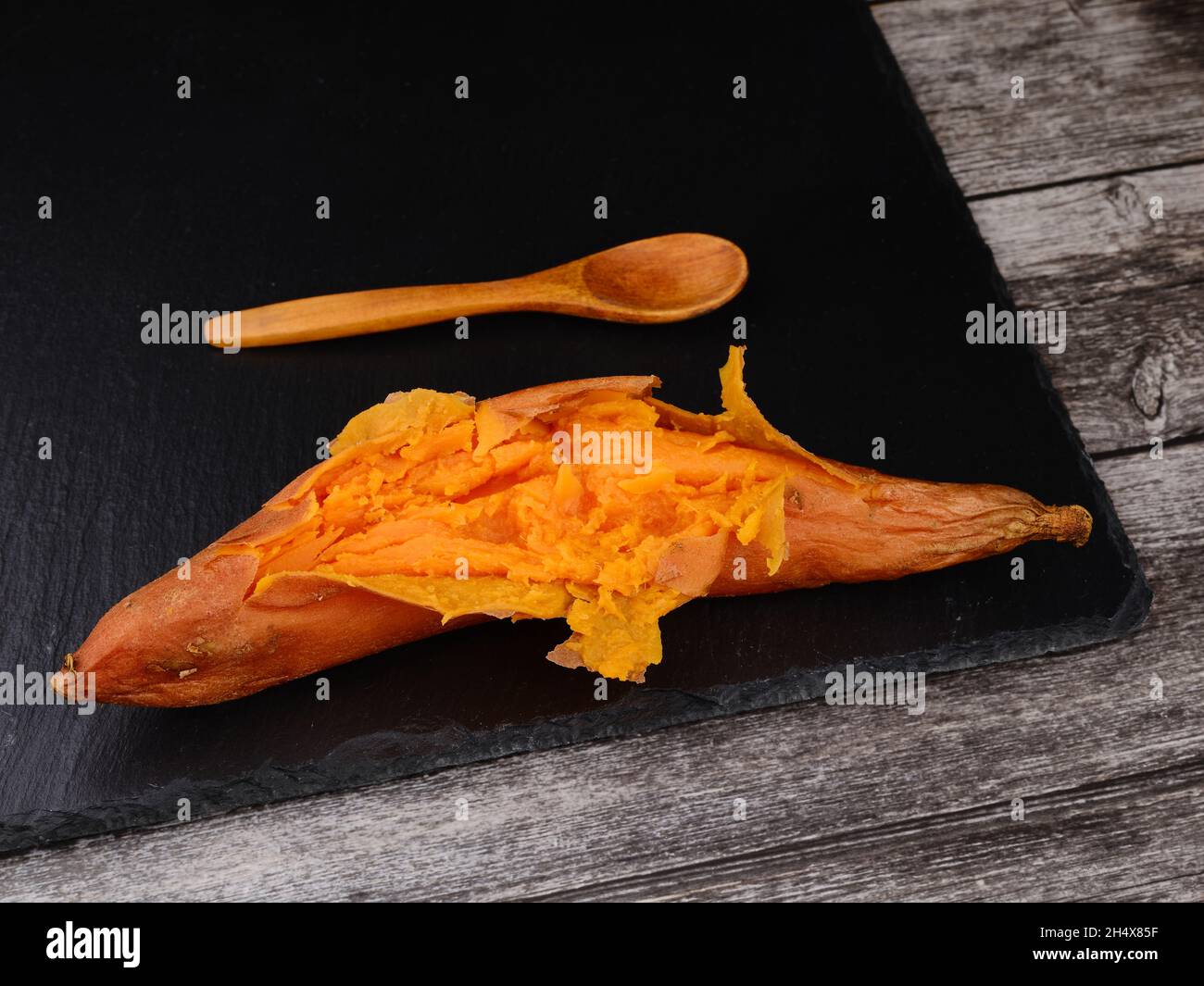 Patate douce cuite sur pierre sombre.Table et cuillère en bois Banque D'Images