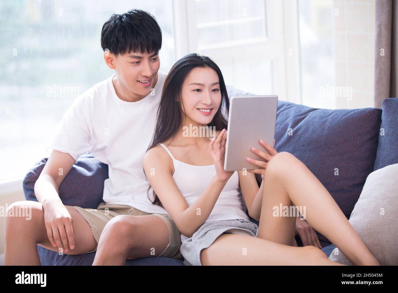 Jeune couple utilisant une tablette numérique sur le canapé Banque D'Images