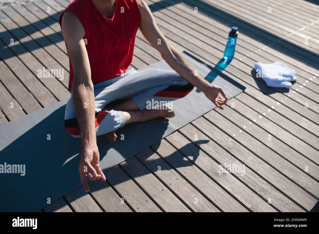 Section basse de l'homme assis en position lotus méditant tout en pratiquant le yoga sur le plancher Banque D'Images