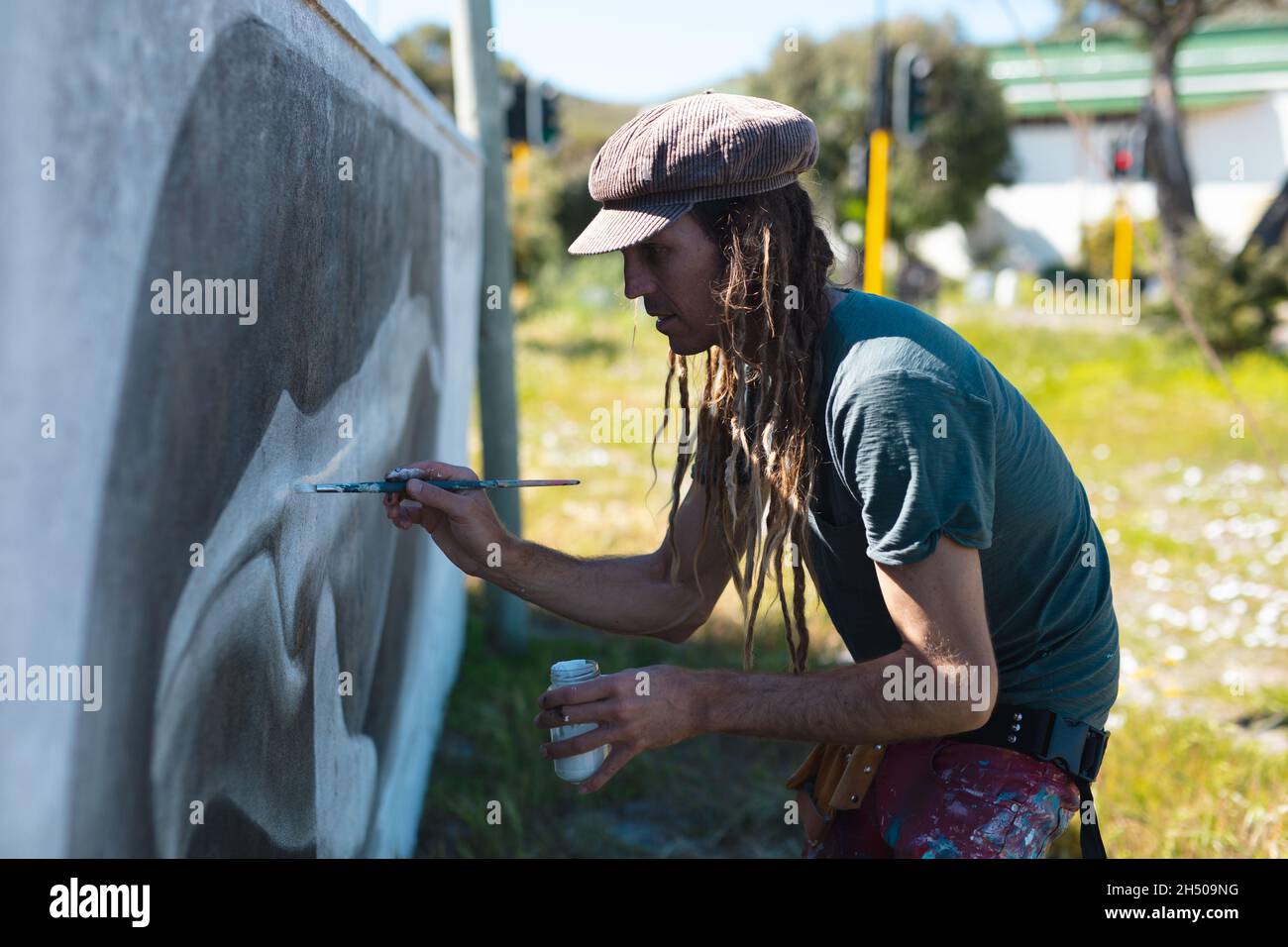 Artiste masculin se concentrant tout en faisant la peinture murale créative de baleine sur le mur avec un pinceau Banque D'Images