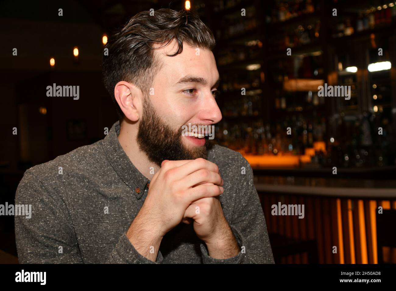 Un homme à barbe blanche est assis dans un restaurant le soir avec différentes expressions du visage. Banque D'Images