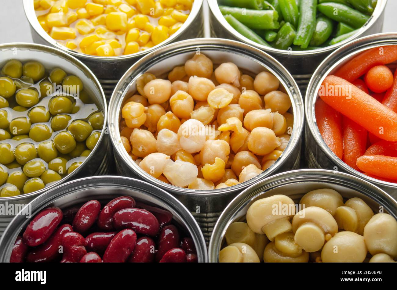 Légumes en conserve dans des boîtes ouvertes sur la table de cuisine. Aliments non périssables à longue durée de conservation Banque D'Images