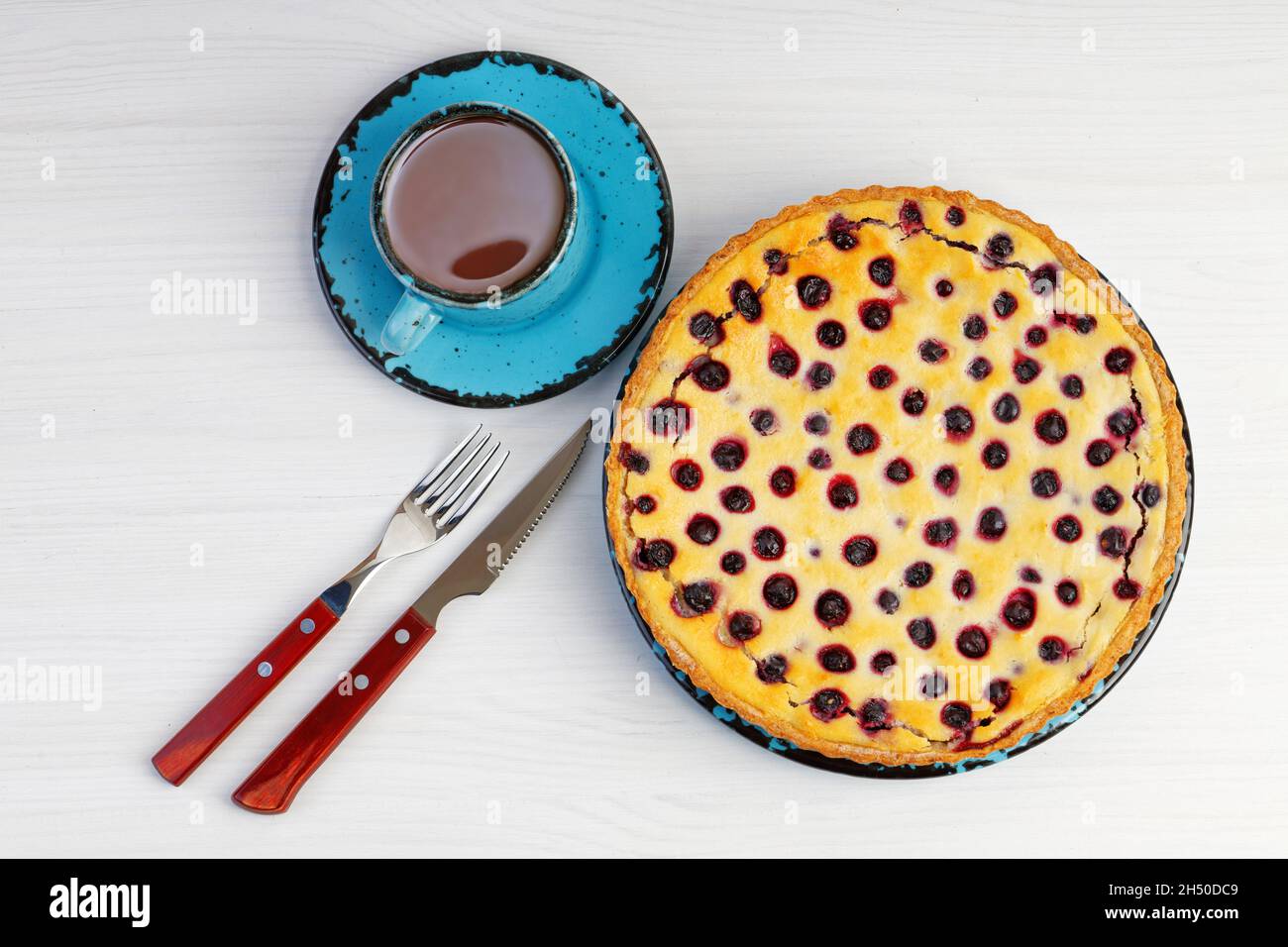 Tarte aux baies maison avec ricotta et cassis et une tasse de thé sur une table en bois blanc.Vue de dessus. Banque D'Images Tarte aux baies maison avec ricotta et cassis et une tasse de thé sur une table en bois blanc.Vue de dessus. Banque D'Images