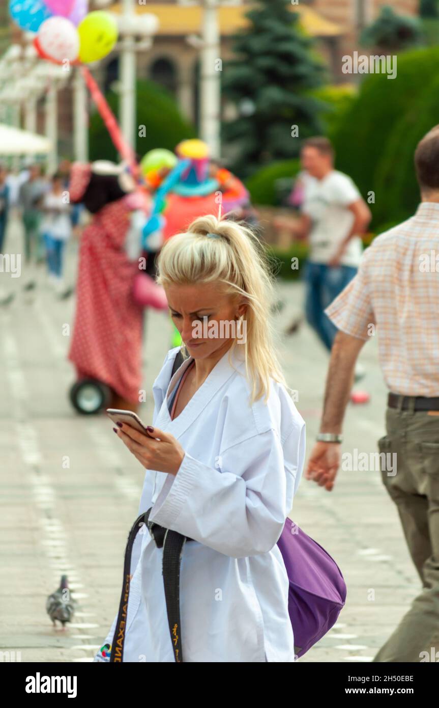 Timisoara, Roumanie - 08 juin 2016: Femme vêtue d'un uniforme de karaté vérifiant son téléphone. De vraies personnes. Banque D'Images