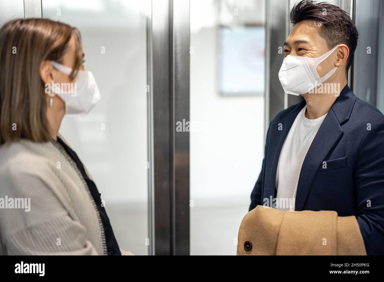 Homme et femme dans des masques médicaux dans l'ascenseur Banque D'Images