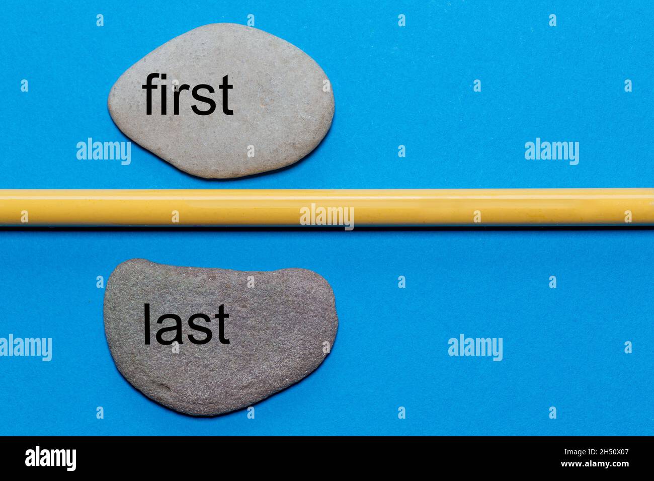 Les mots premier et dernier sont écrits sur des pierres naturelles lisses séparées par un crayon jaune.Le fond est isolé en bleu et a beaucoup d'espace Banque D'Images Les mots premier et dernier sont écrits sur des pierres naturelles lisses séparées par un crayon jaune.Le fond est isolé en bleu et a beaucoup d'espace Banque D'Images