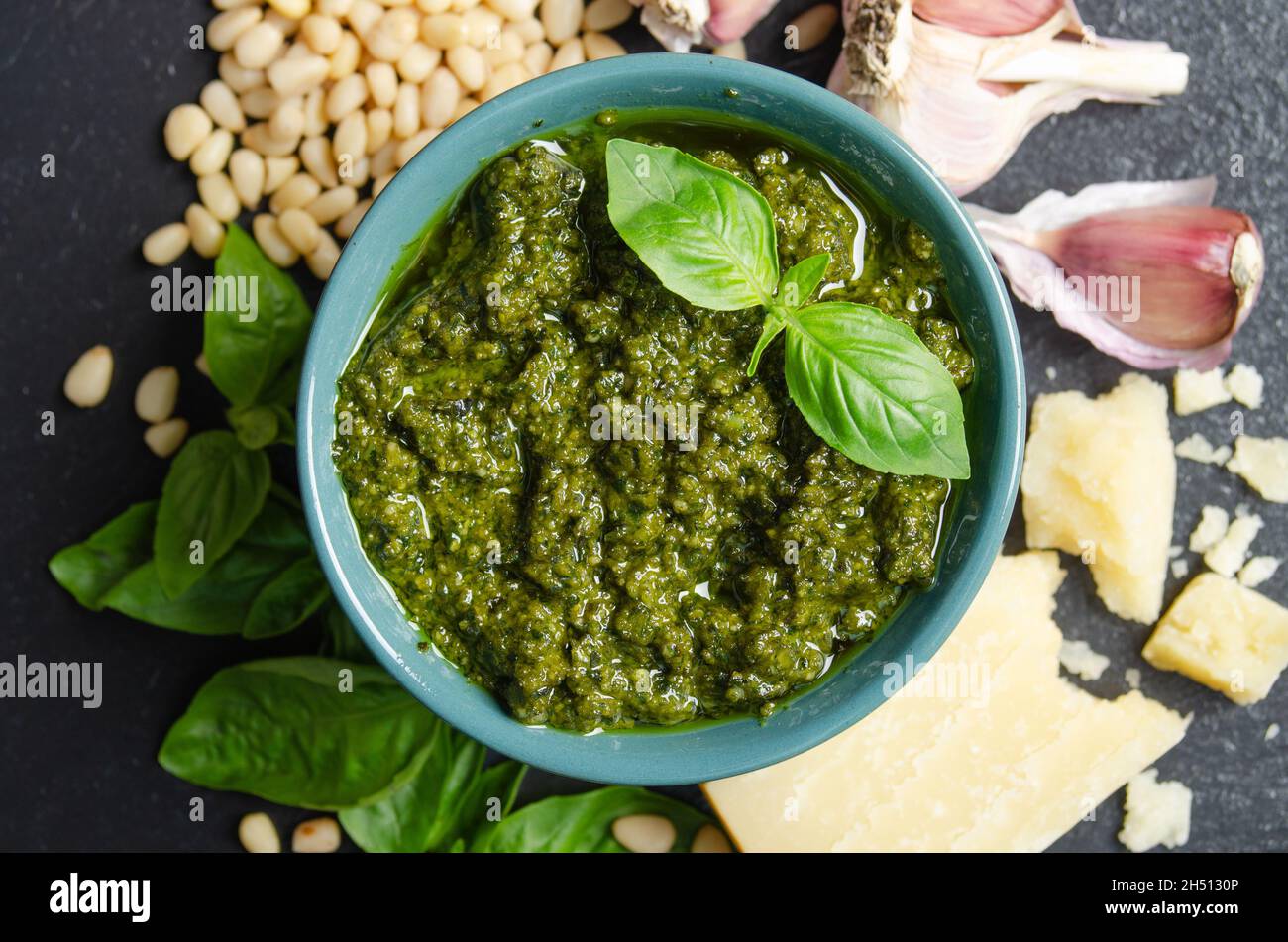 Vue à plat sur le bol vert avec sauce pesto génovese et ses ingrédients au centre du plateau en ardoise Banque D'Images