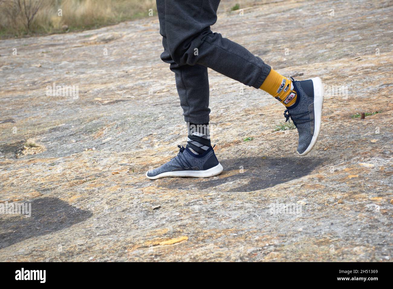 Vue latérale des jambes de l'homme marchant sur les empreintes de dinosaures d'iguanodon.Gisement de Regumiel de la Sierra, Burgos, Espagne. Banque D'Images