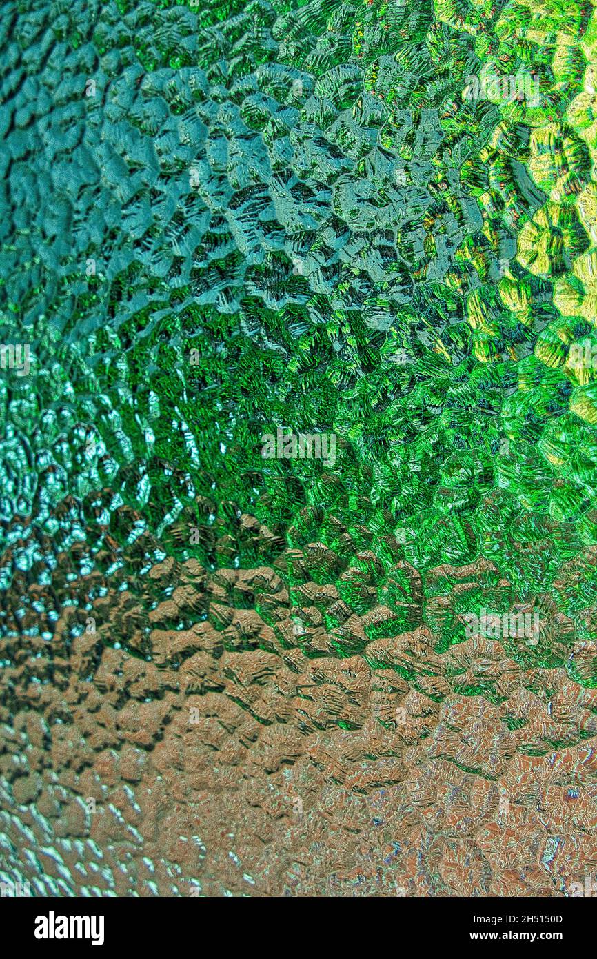 Détail d'une vue à travers une fenêtre avec verre à motifs.Motif abstrait en nuances de jaune, vert, marron et gris Banque D'Images