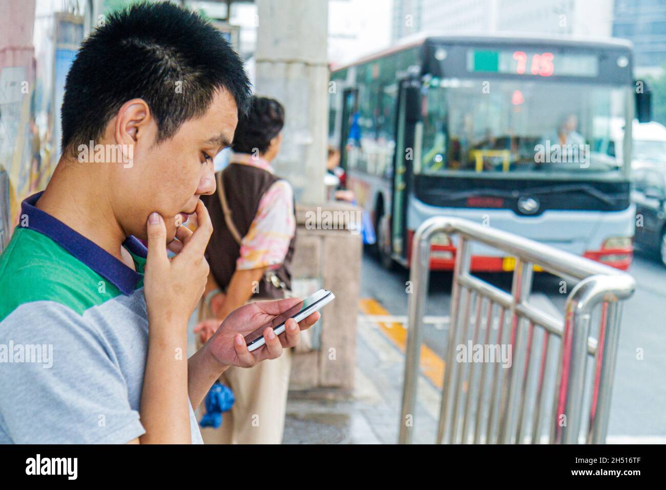 Beijing Chine,Chinois,Xicheng Guang an Men Nei Da Jie,Guanganmen Outer Street,homme asiatique mâle,smartphone mobile téléphone portable SMS messagerie arrêt de bus Banque D'Images