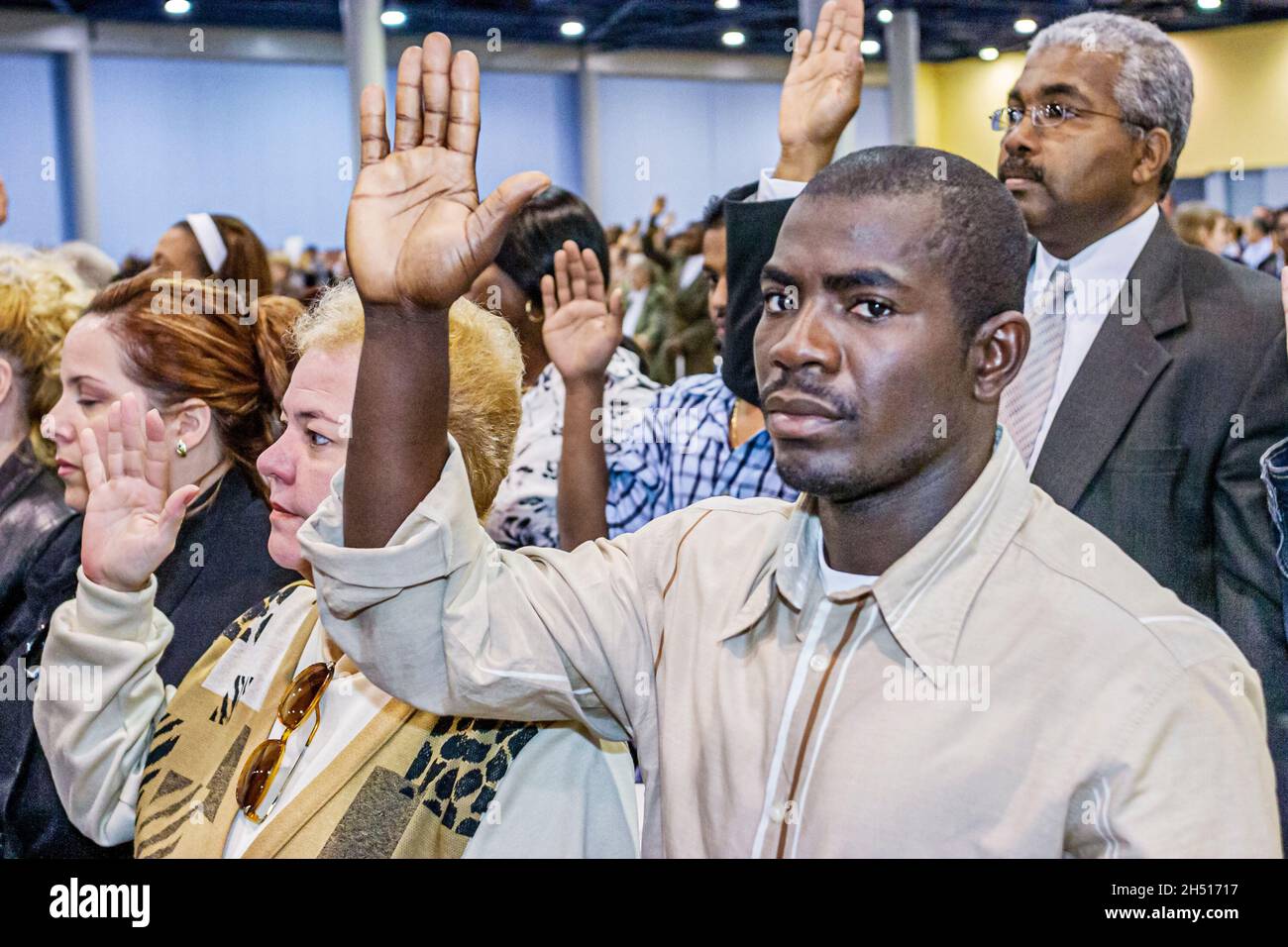 Miami Beach Florida, Centre des congrès, US Citizenship Ceremony, immigrants assertant dans les mains droites élevé Black man Banque D'Images