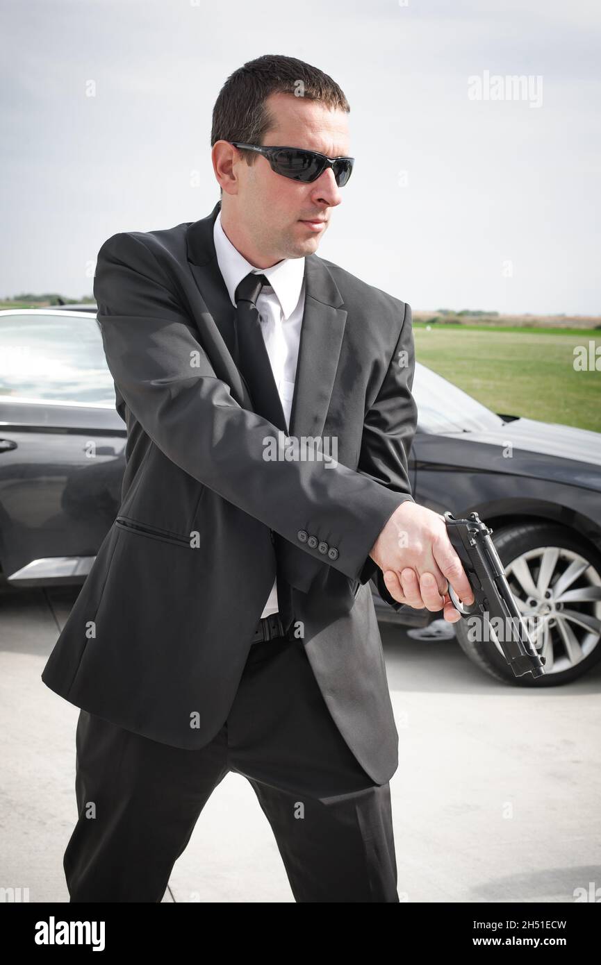 Agent espion professionnel avec pistolet.Police de sécurité en costume noir  civil avec lunettes de soleil.Protection de sécurité rapprochée Photo Stock  - Alamy