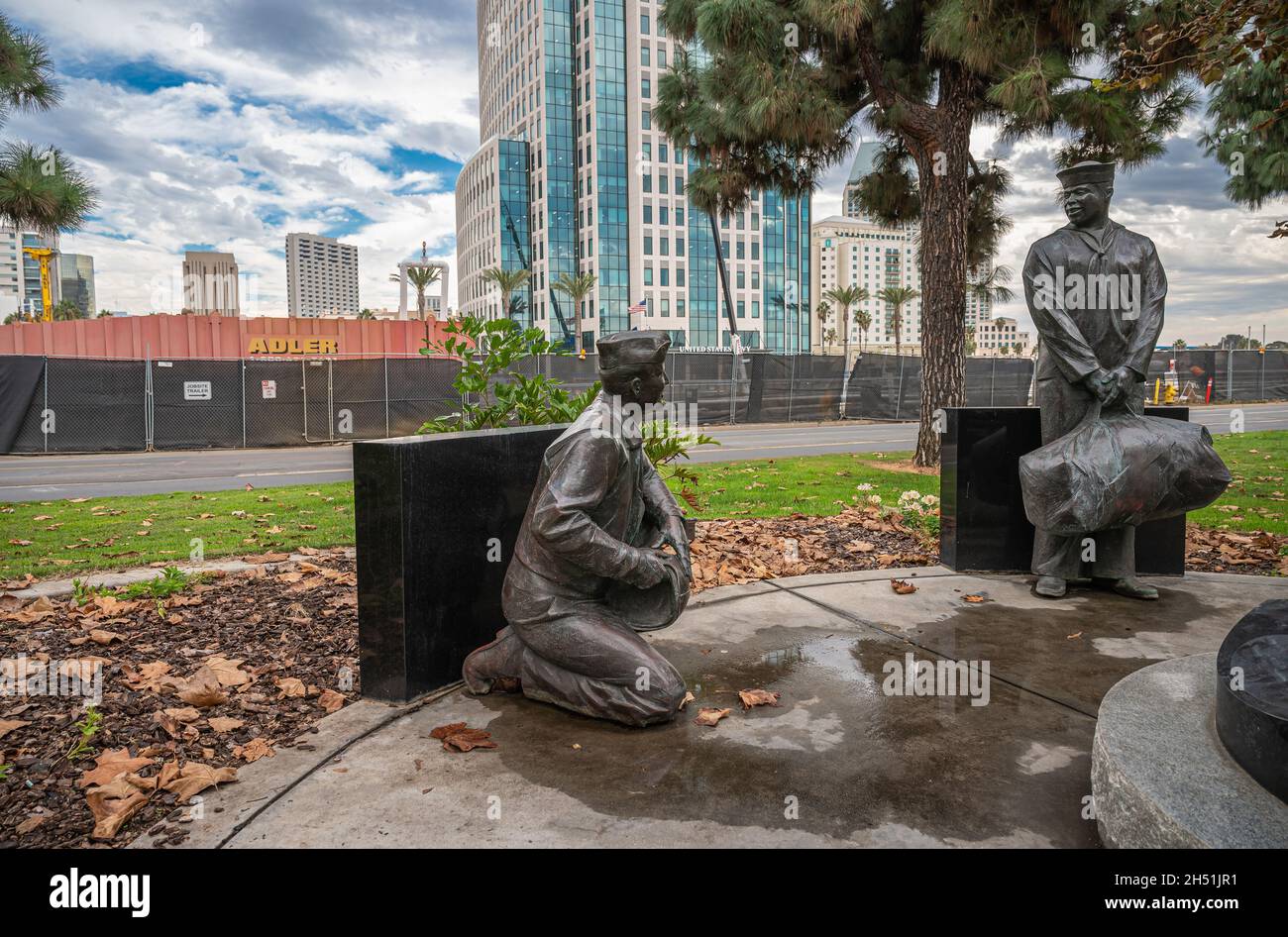 San Diego, Californie, États-Unis - 4 octobre 2021 : promenade Embarcadero.2 statues de marins mâles au USA Aircraft Carrier Memorial.Feuillage vert et bu marine Banque D'Images