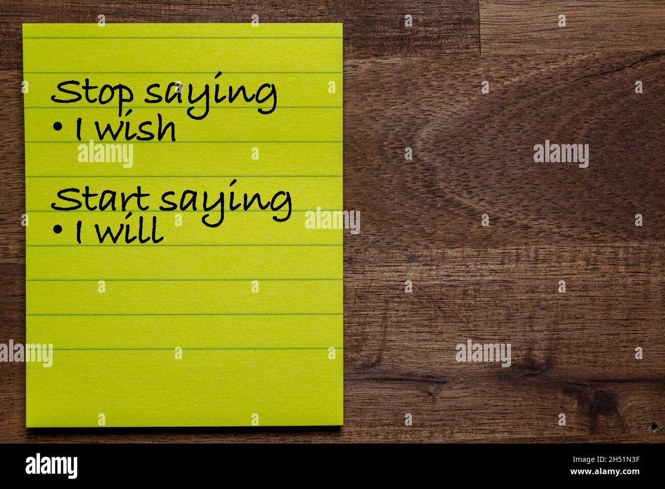 Autocollant jaune avec des lignes sur un fond en bois foncé avec l'écriture de la sagesse de la vie: Arrêter de dire que je voudrais commencer à dire que je vais Banque D'Images