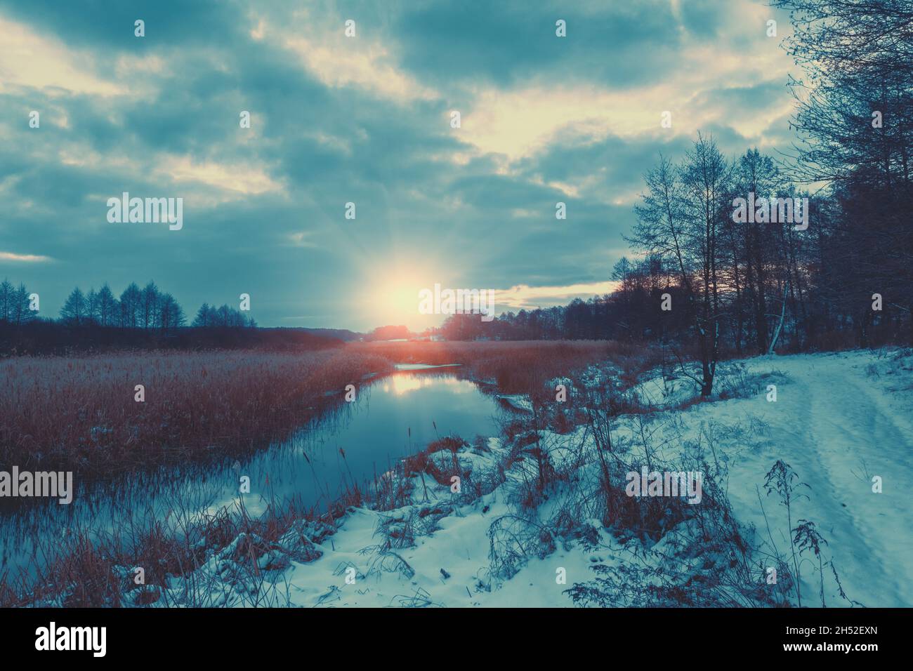 Paysage rural en hiver.Vue sur le ruisseau et ciel nuageux au coucher du soleil. Banque D'Images