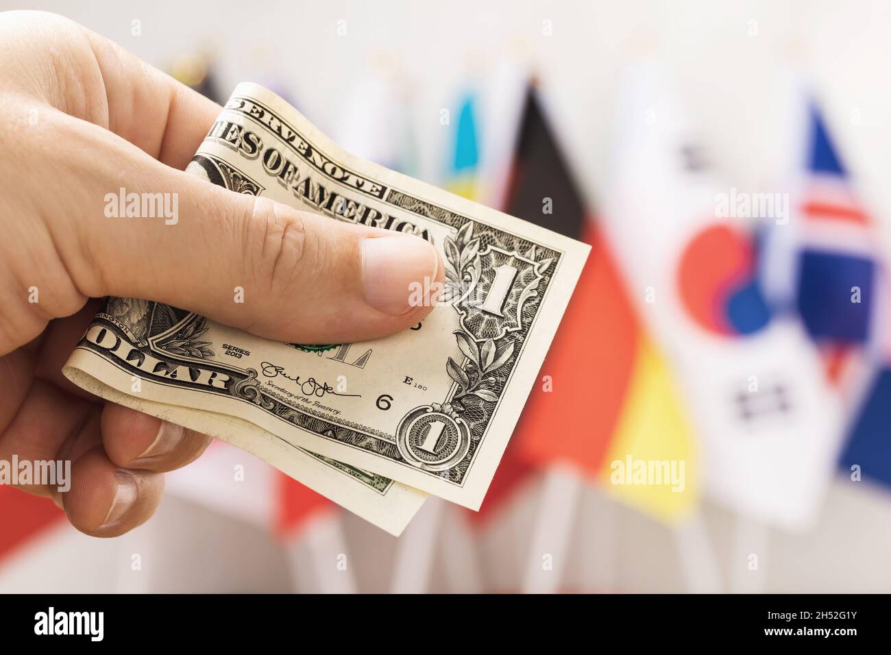 Un dollar en main dans le contexte des drapeaux des différents pays, le concept de la monnaie de réserve mondiale Banque D'Images