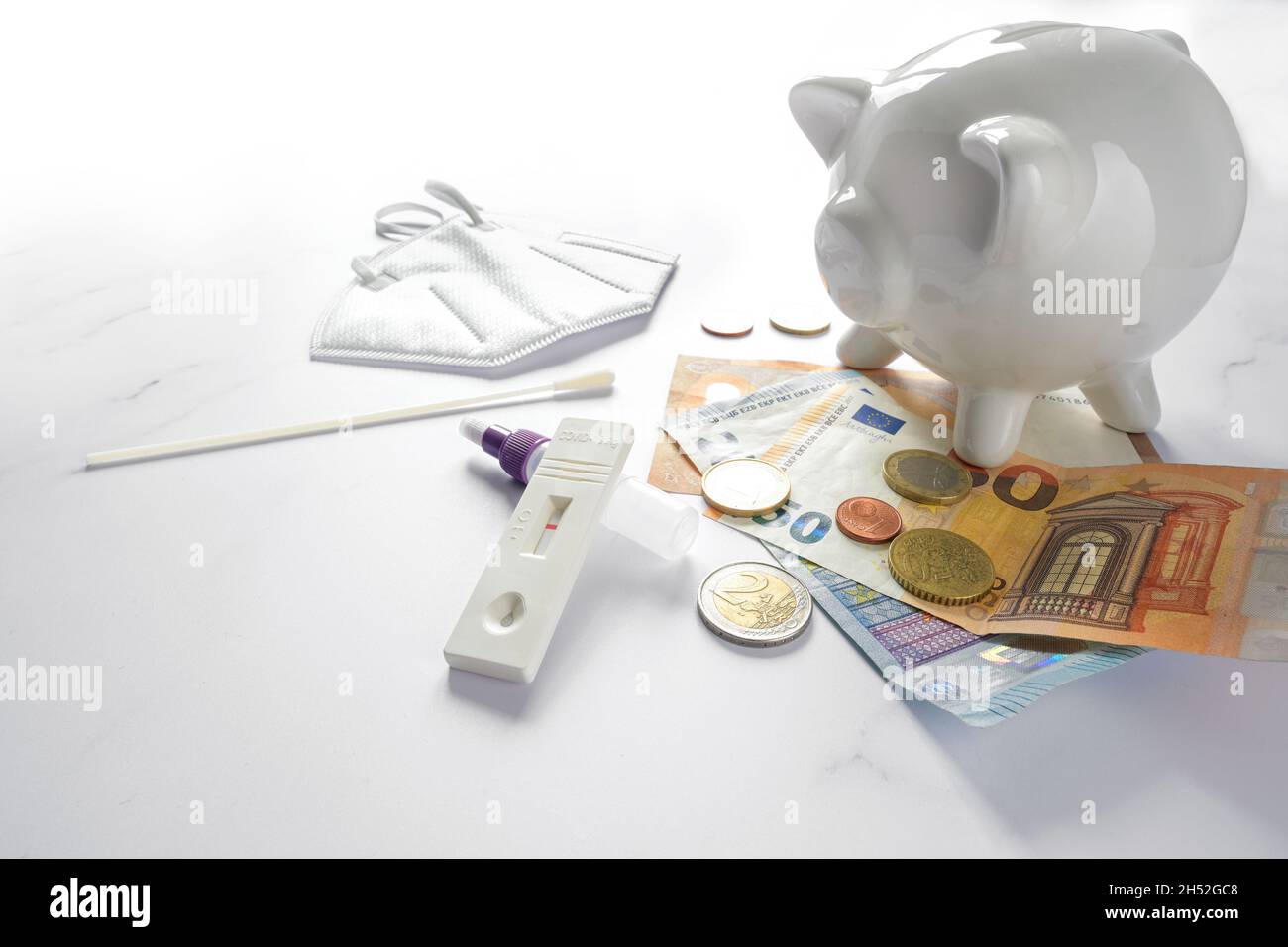 Test rapide Covid-19, euro monétaire et une banque de pigeons sur une table en marbre, les Allemands non vaccinés doivent payer pour les tests pour participer à la dur de la vie publique Banque D'Images