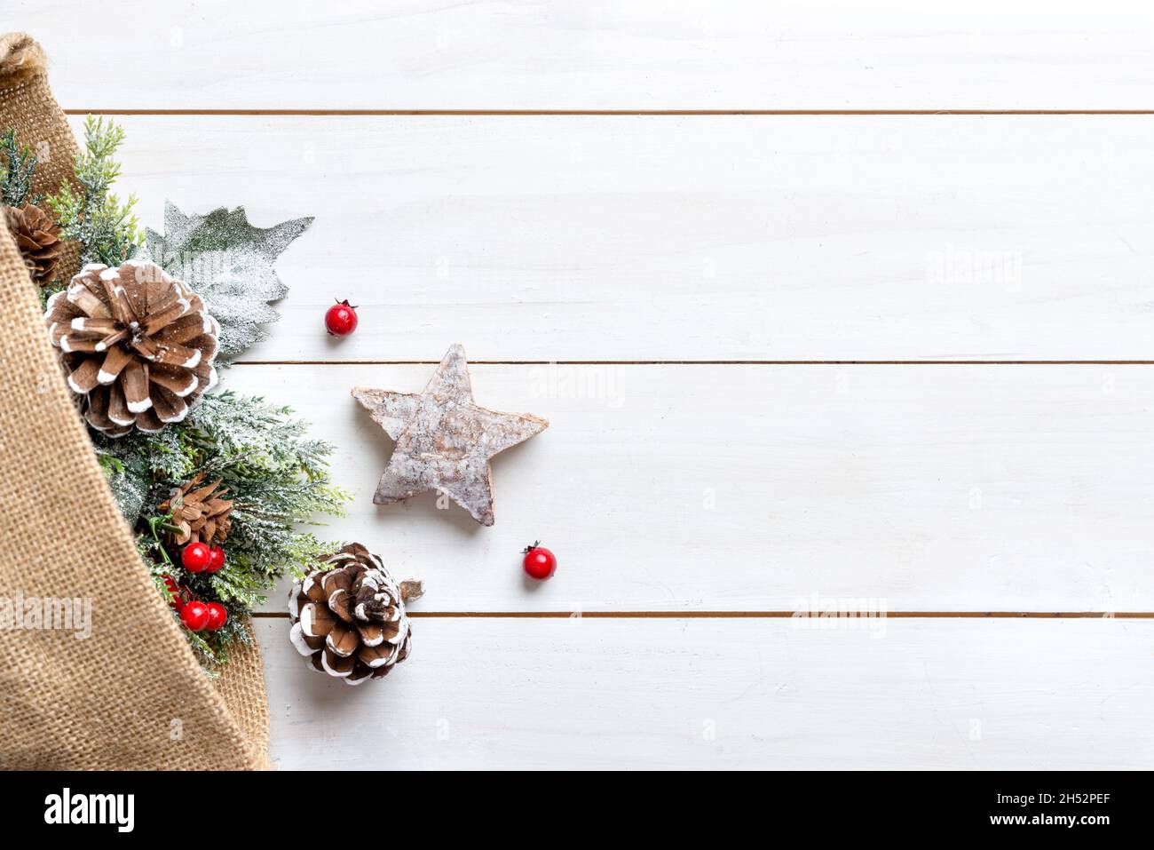 Composition de Noël sur une table en bois blanc avec un sac de décorations sortir.Espace libre à côté du texte de message d'accueil Banque D'Images