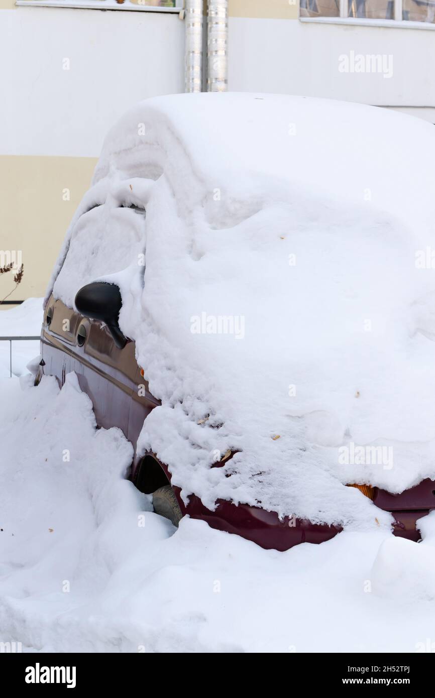 voiture rouge abandonnée en hiver garée sous une grande couche de neige par une journée ensoleillée et froide Banque D'Images