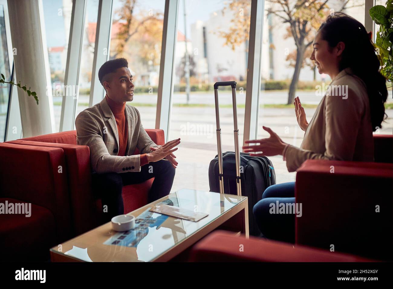 Homme et femme souriants assis dans le hall d'un hôtel Banque D'Images