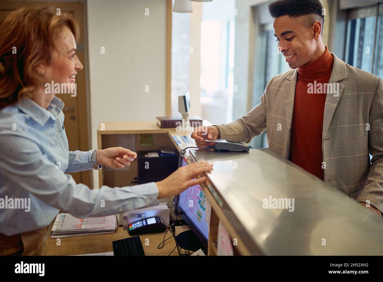 Homme d'affaires payant avec une carte à une réceptionniste souriante Banque D'Images