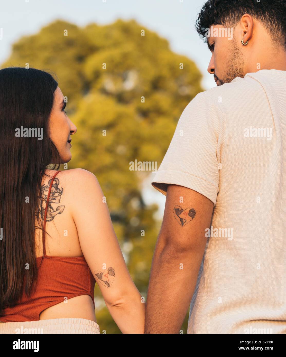 Couple avec le même tatouage dans le bras tenant les mains dans un parc Banque D'Images