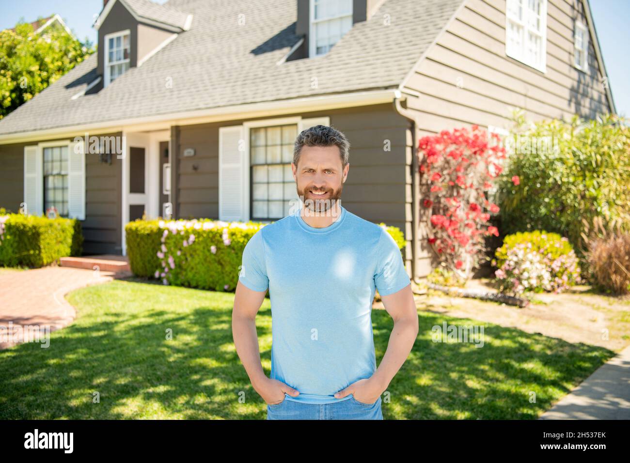 heureux homme mature debout à l'extérieur à la maison, propriétaire Banque D'Images