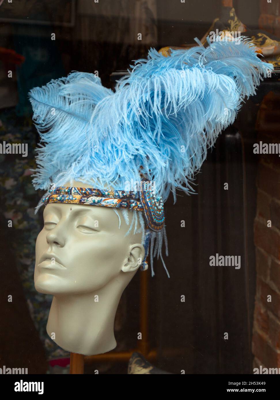 Une tête de plume bleue sur Une tête de mannequin verte dans la fenêtre d'Un Milliner's Shop, Lymington, Royaume-Uni Banque D'Images