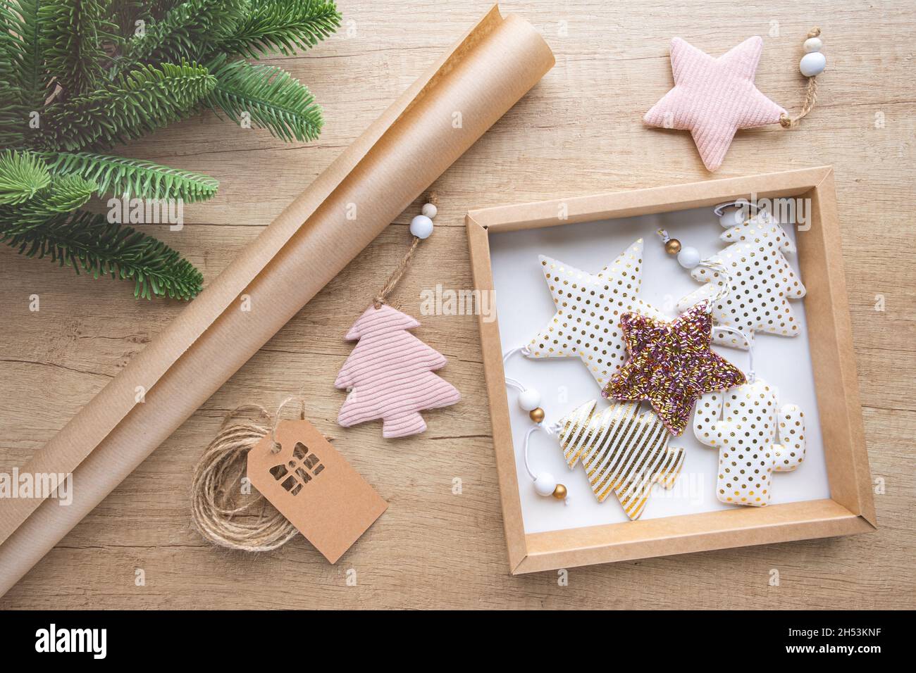 Boîte cadeau avec jouets de Noël en tissu, rouleau de papier kraft, branche de sapin sur fond de bois.Concept d'emballage écologique, zéro déchet.Emballage cadeau Banque D'Images