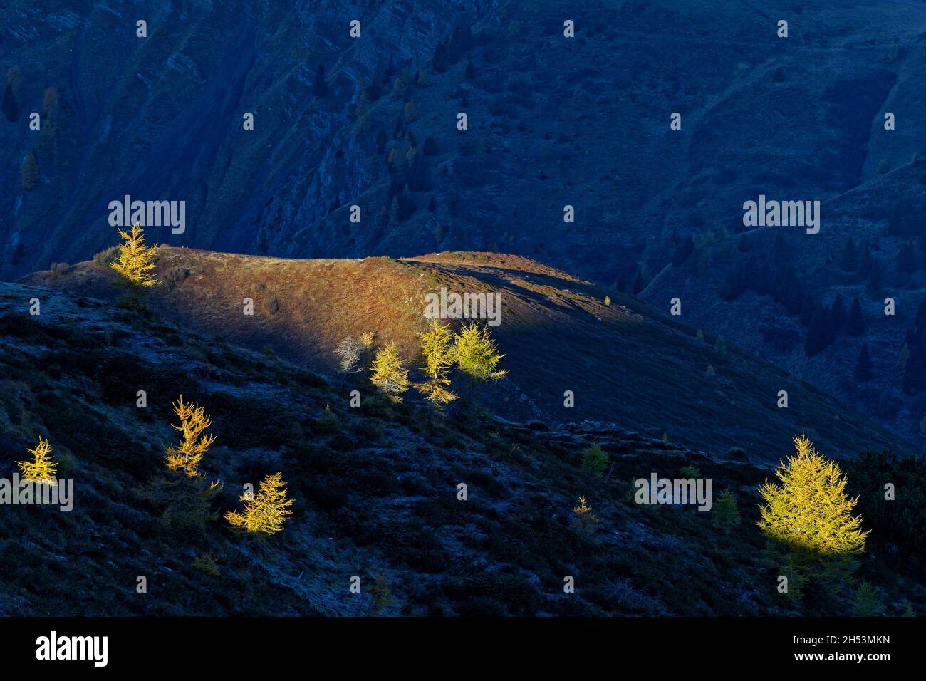 Le soleil s'élève au sommet des larches avec des lumières et des ombres sur les collines autour Banque D'Images